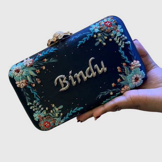 Cannish Pitara navy blue personalized clutch with hand-embroidered floral details and metallic name lettering.