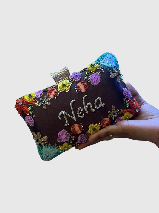 Cannish Pitara personalized brown clutch with hand-embroidered floral details and the name Neha in silver lettering.