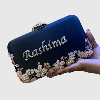 Cannish Pitara navy blue personalized clutch with floral beadwork and custom name embroidery held in a hand